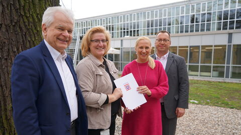 Ralf-Rainer Klatt, Vizepräsident des Landessportbundes Hessen, Juliane Kuhlmann, Präsidentin des Landessportbundes Hessen, Sportministerin Diana Stolz und Andreas Klages, Hauptgeschäftsführer des Landessportbundes Hessen stehen nebeneinander vor einem Gebäude mit dem Förderbescheid in Händen.