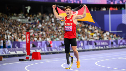 Mann steht in Arena und hält Deutschlandfahne in die Höhe. Auf seinem Trikot steht "Germany" und der Name "Streng" in Großbuchstaben