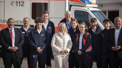 Das Team der DRK sowie Innenminister Poseck und Gesundheitsministerin Stolz stehen vor der Rettungswache Flörsheim-Wicker.