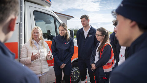Gesundheitsministerin Stolz besucht die DRK-Rettungswache Flörsheim-Wicker Gesundheitsministerin Stolz steht mit Rettungssanitätern vor einem Krankenwagen.