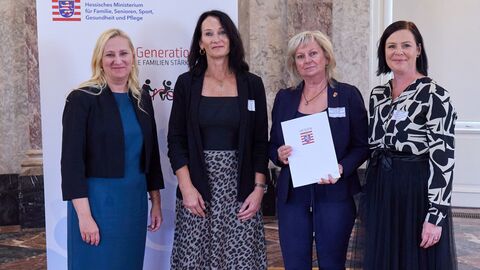 Die Preisträgerinnen des Projekts „Wissen stärkt, Aktivität belebt und Gemeinschaft verbindet“ werden ausgezeichnet. Familienministerin Diana Stolz steht mit drei weiteren Personen vor der Kamera.