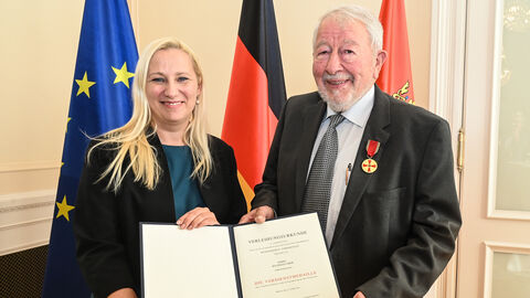 Eine Frau und ein Mann halten eine Urkunde gemeinsam hoch.