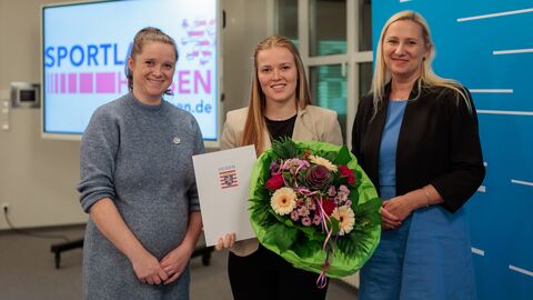 Anna-Lena Pietsch vom TSG Hofgeismar. 3 Frauen stehen nebeneinander und halten Blumen und eine Urkunde hoch.