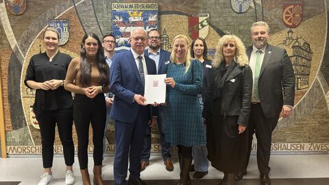 Mehrere Frauen und Männer stehen nebeneinander vor einer Wand.