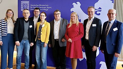 9 Männer und Frauen stehen nebeneinander.