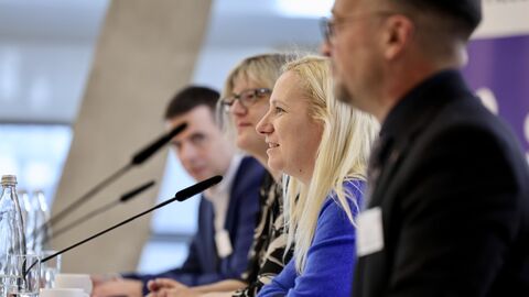 Pressekonferenzsituation Mehrere Menschen sitzen vor Mikrofonen