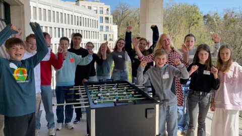 Familienministerin Stolz steht mit einer Gruppe Jungen und Mädchen um einen Tischkicker herum.