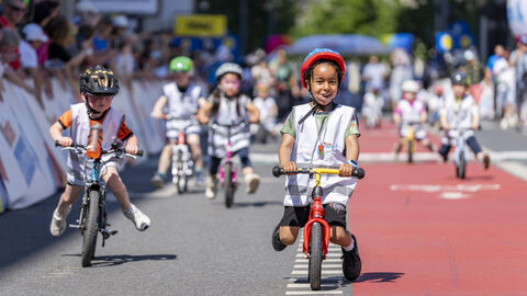 Viele Kinder fahren mit ihren Laufrädern über eine Rennstrecke.
