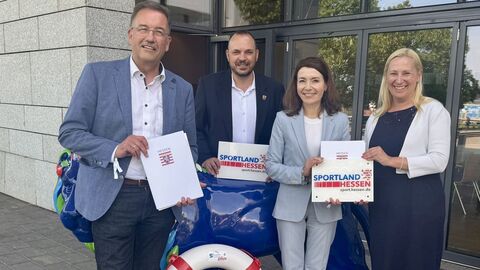 Mehrere Personen stehen mit einem Rettungsring zusammen und halten Förderbescheide in Händen.