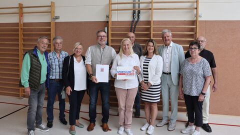 Mehrere Personen stehen nebeneinander in einer Sporthalle.