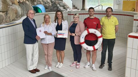 Mehrere Personen stehen in leerem Schwimmbecken.