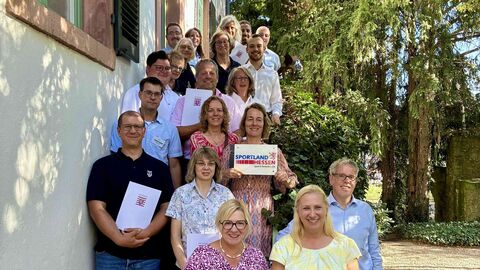 Mehrere Personen stehen auf Treppe aufgereiht und schauen in Kamera