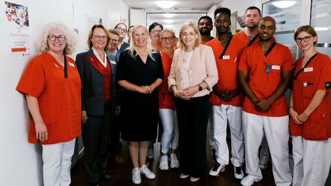 Bundesgesundheitsministerin Nina Warken und Gesundheitsministerin Diana Stolz mit Pflegekräften stehen in einer Reihe.