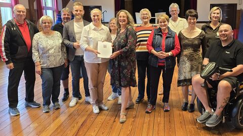 Mehrere Personen stehen zusammen, eine Person sitzt im Rollstuhl.