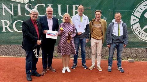 Sechs Personen stehen auf einem Tennisplatz.