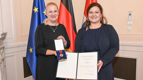 Diana Stolz hält die Medaille in den Händen und steht neben Nadine-Yvonne Merten welche eine Urkunde in die Kamera hält.