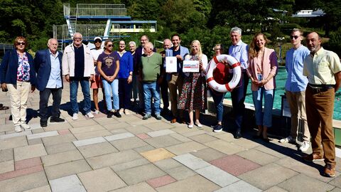 Diana Stolz steht mit einer Gruppe von Menschen vor einem Freibadbecken