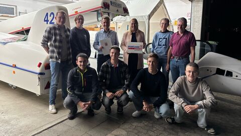 Mehrere Menschen stehen vor Segelflugzeug