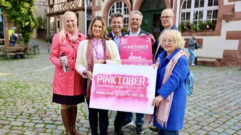 Pinktober Mehrere Personen stehen zusammen und halten ein Plakat in den Händen