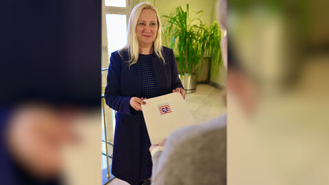 Familienministerin Stolz übergibt eine Urkunde.