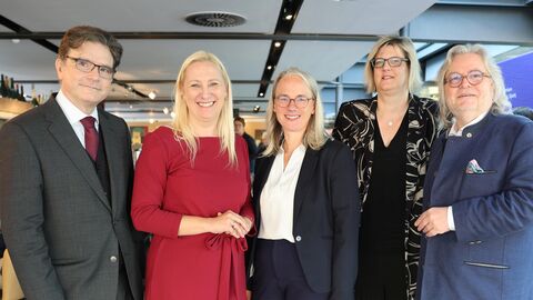 Fünf festlich gekleidete Personen stehen nebeneinander und schauen in die Kamer.