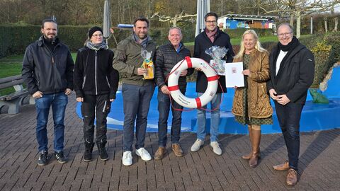 Mehrere Personen stehen zusammen. Eine Person hält einen Schwimmreifen.