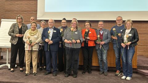 Staatssekretäring Dr. Sonja Optendrenk steht mit den Geehrten auf einer Bühne.
