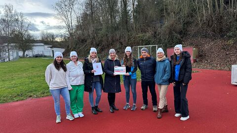 Sieben Frauen und ein Mann stehen nebeneinander auf einer Tartanbahn.
