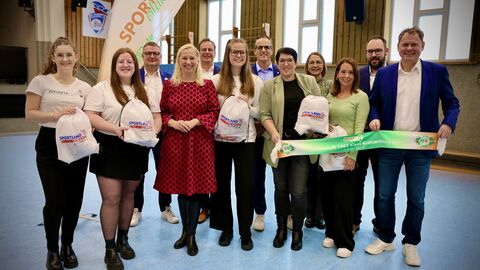 Diana Stolz steht mit circa 10 Personen in einer Turnhalle